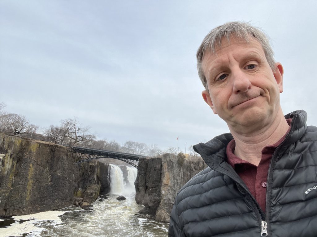 RoamingMonk at Paterson Great Falls National Historical Park in New Jersey, with the Great Falls and iron arch bridge visible behind.