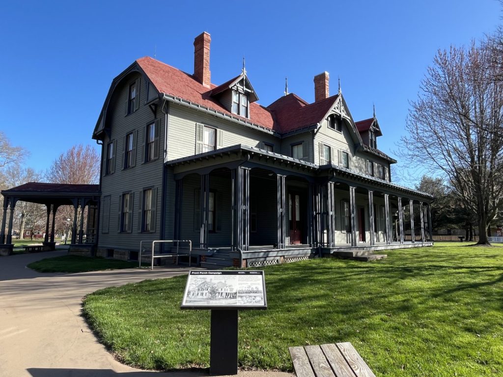 Lawnfield front porch exterior with interpretive panel and blue sky at James A. Garfield National Historic site