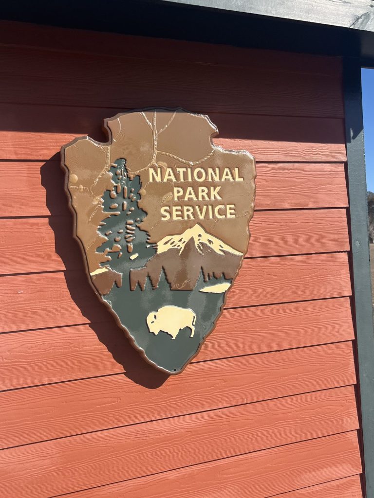 National Park Service arrowhead sign mounted on red wooden building siding at Tuskegee Airmen NHS