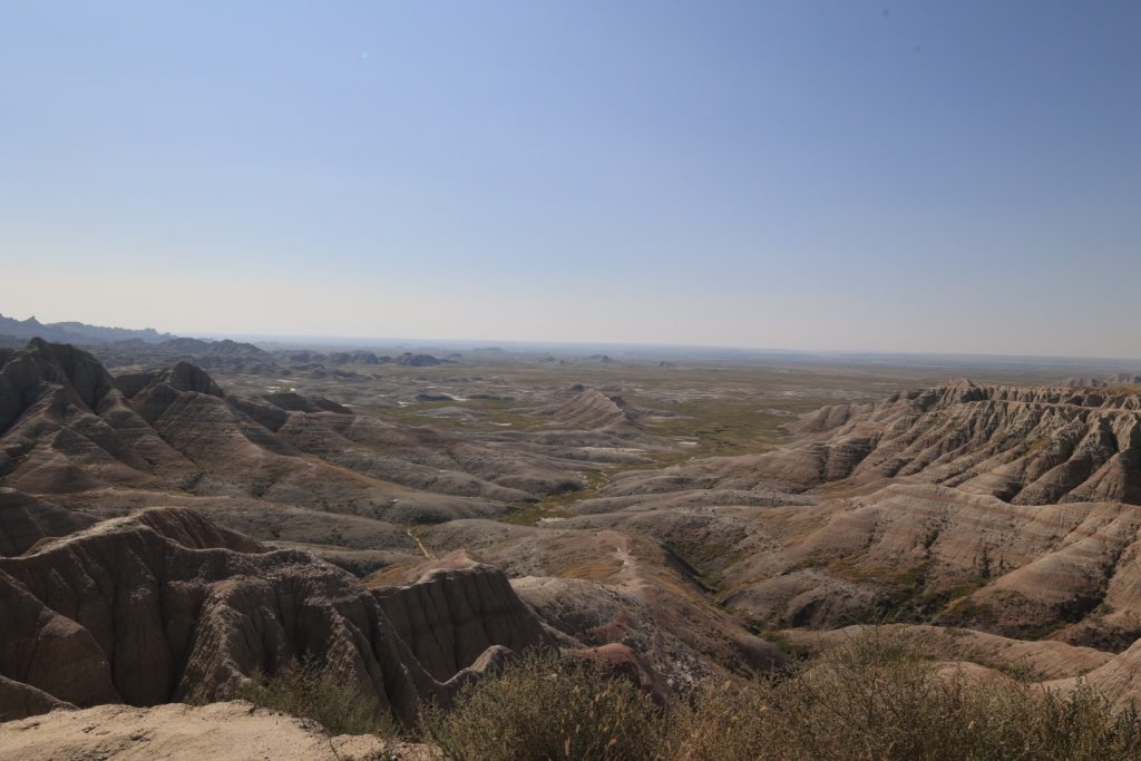 Vast expanse of eroded Badlands National Park formations under a deep blue summer sky