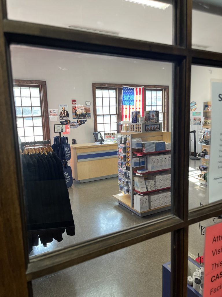 iew through the bookstore window showing interior displays and American flag at Tuskegee NHS
