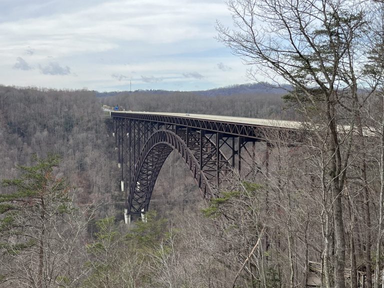 New River Gorge Bridge arch viewed through bare winter trees from Fayette Station overlook area