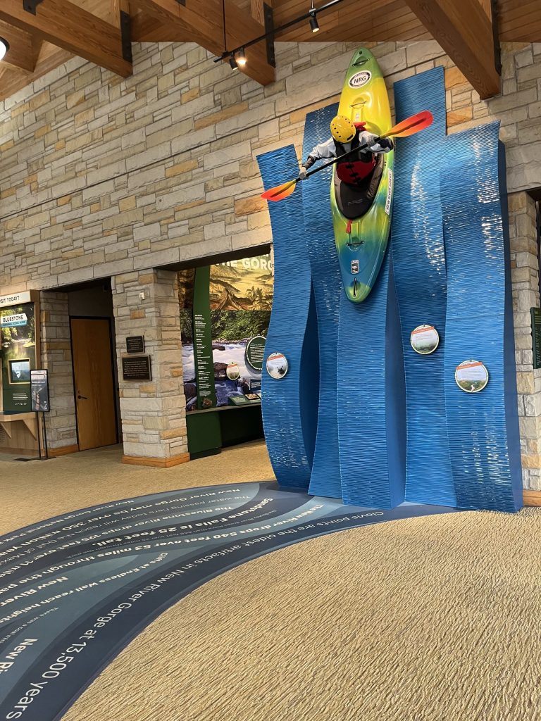 Yellow and green whitewater kayak mounted on display above river exhibit at Canyon Rim Visitor Center New River Gorge