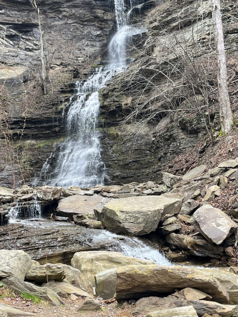 Tall multi-tiered waterfall dropping over rocky ledges surrounded by bare trees at New River Gorge area West Virginia