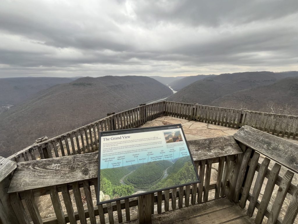 The Grand View overlook platform at New River Gorge with interpretive sign and sweeping canyon vista under cloudy skies