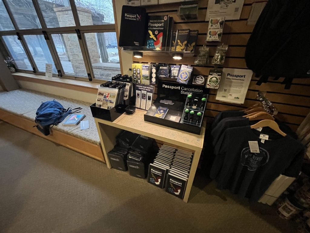 National Park passport stamp cancellation station with passport books and merchandise at Sandstone Visitor Center