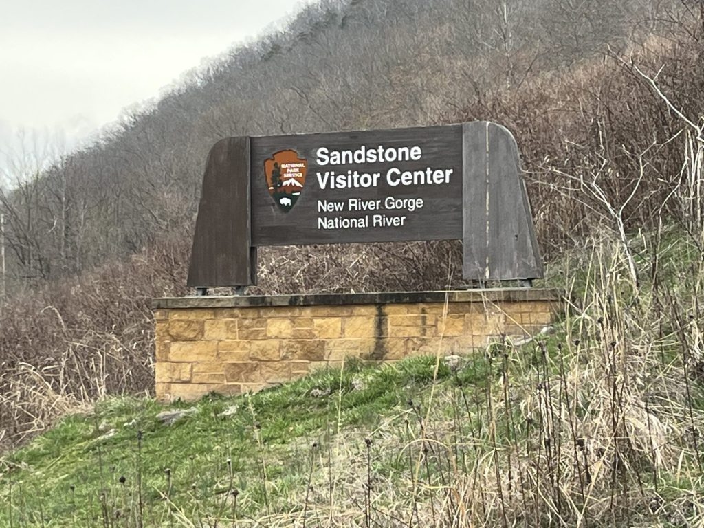 Sandstone Visitor Center entrance sign for New River Gorge National River with stone base 